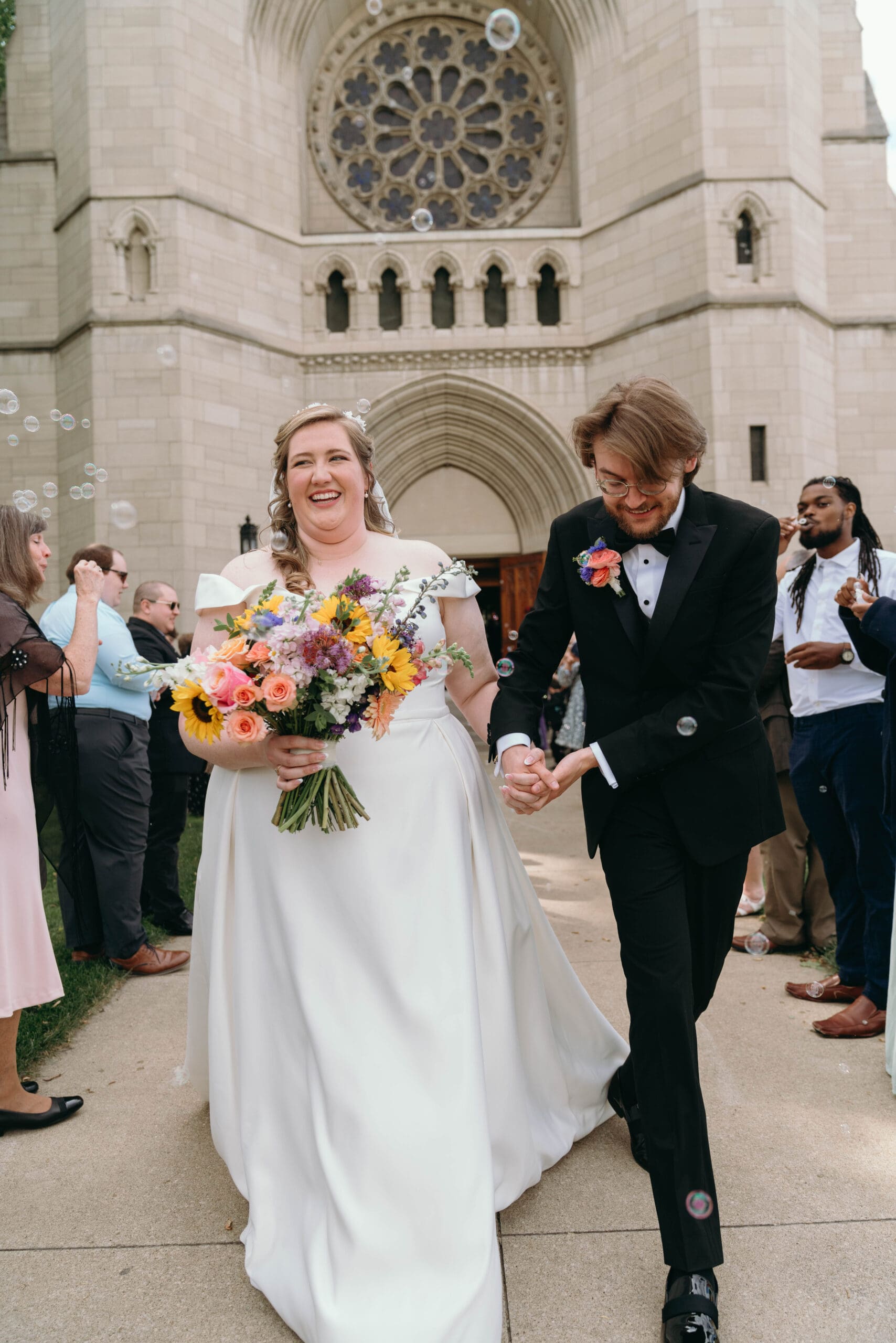 A bride and groom being photographed by Cassandra Lee Photo exiting their wedding ceremony with bubbles.